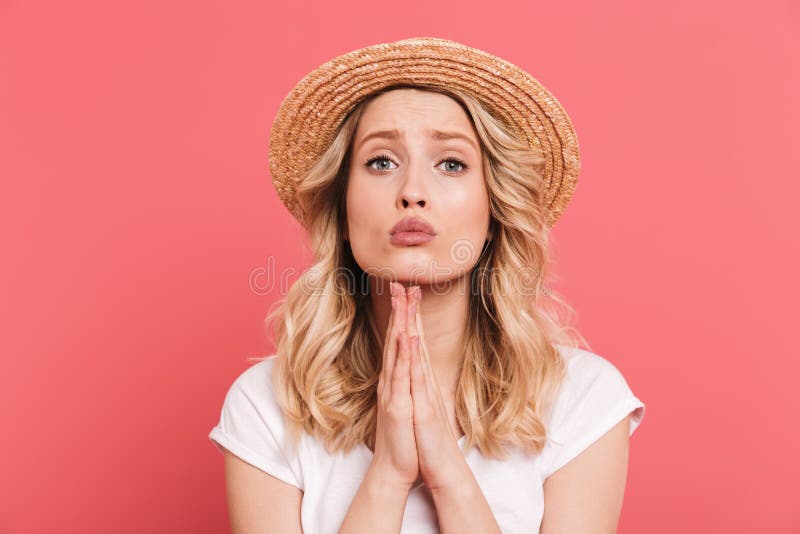 Portrait of elegant blond woman 20s wearing straw hat keeping palms together for pray