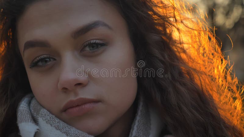 Portrait en gros plan de la fille caucasienne assez aux cheveux bouclés observant sérieusement et directement dans la caméra dans images stock Portrait en gros plan de la fille caucasienne assez aux cheveux bouclés observant sérieusement et directement dans la caméra dans images stock