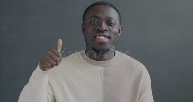 Portrait en mouvement lent d'un Africain Américain heureux montrant un geste de la main avec un pouce souriant banque de vidéos