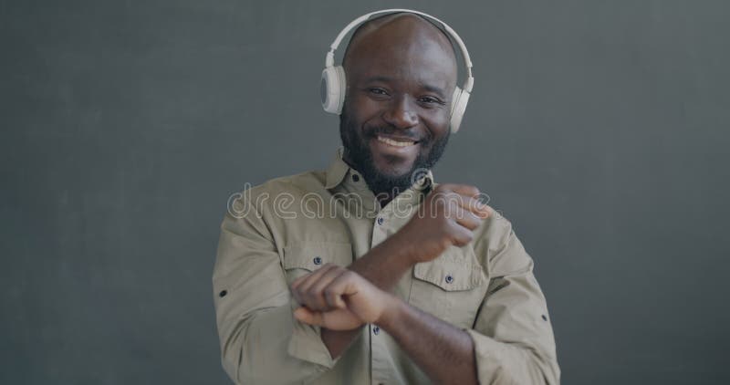 Portrait en mouvement lent d'un Africain Américain heureux écoutant de la musique avec des écouteurs dansant banque de vidéos