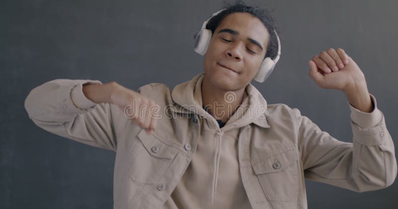 Portrait en mouvement lent d'un Africain Américain heureux écoutant de la musique avec des écouteurs dansant banque de vidéos