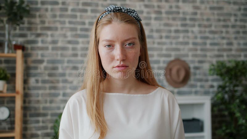 Portrait en mouvement lent d'une jeune femme avec un visage sérieux regardant la caméra à l'intérieur clips vidéos