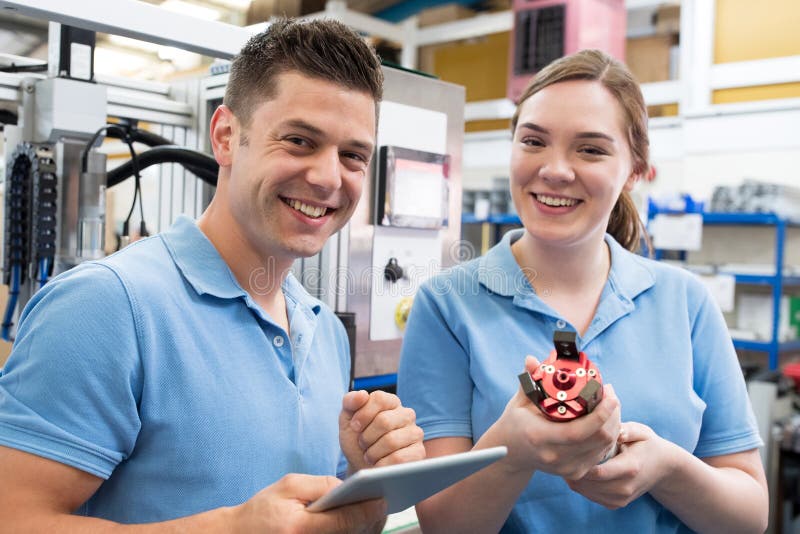 Portrait Of Engineer And Apprentice Examining Component In Factory royalty free stock photography