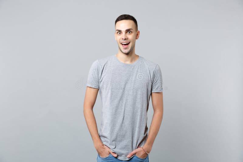 Portrait of excited young man in casual clothes keeping mouth open, holding hands in pockets isolated on grey wall royalty free stock images Portrait of excited young man in casual clothes keeping mouth open, holding hands in pockets isolated on grey wall royalty free stock images
