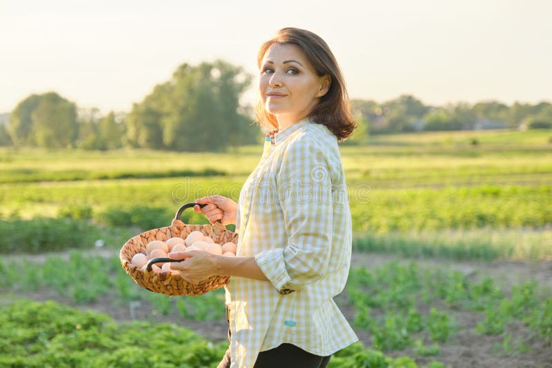 Portrait extérieur de femme d'agriculteur avec le panier des oeufs frais de poulet, ferme photo stock Portrait extérieur de femme d'agriculteur avec le panier des oeufs frais de poulet, ferme photo stock