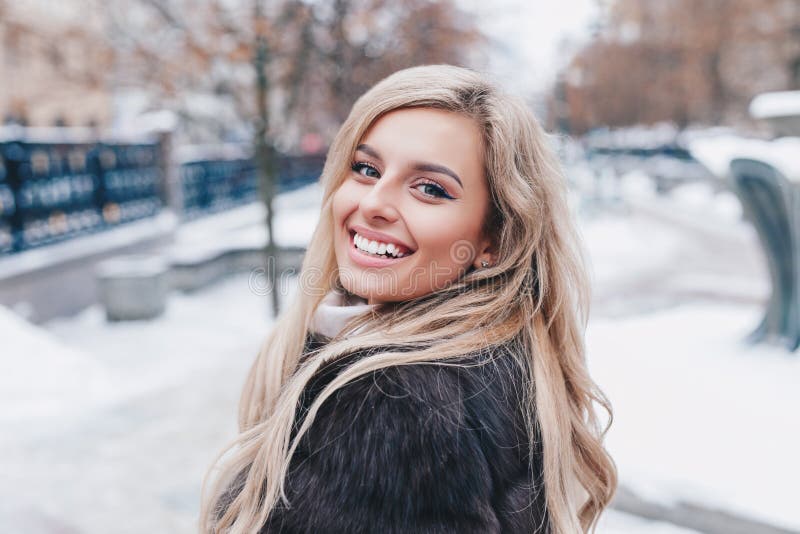 Portrait extérieur de la jeune belle fille de sourire à la mode portant le manteau à la mode d'hiver de fourrure, posant dans la images stock Portrait extérieur de la jeune belle fille de sourire à la mode portant le manteau à la mode d'hiver de fourrure, posant dans la images stock
