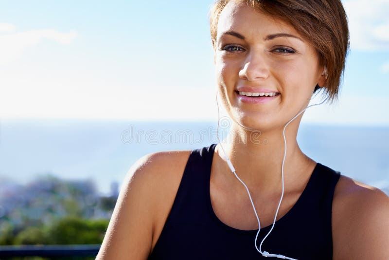 Portrait extérieur ou femme heureuse prête pour l'exercice de remise en forme ou le bien-être sain dans le parc naturel. écoute du ciel ou visage du sportif en pause entraînement avec de la musique ou des écouteurs de confiance.