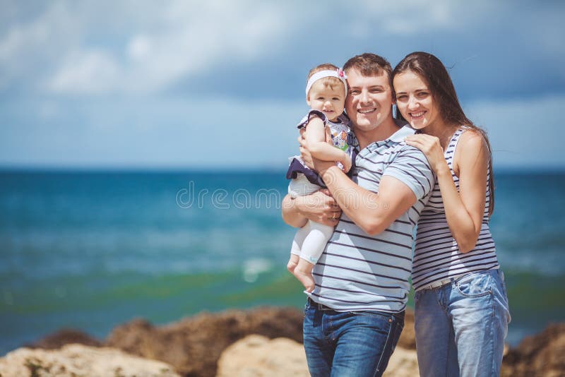 Portrait of family of three having fun together by the ocean shore and enjoying the view. Outdoors