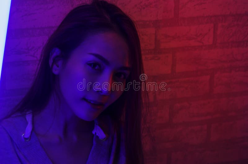 Portrait fashion of an Asian woman in neon-violet and red light that shines in the dark with beauty and sexy, seductive, charming stock image Portrait fashion of an Asian woman in neon-violet and red light that shines in the dark with beauty and sexy, seductive, charming stock image