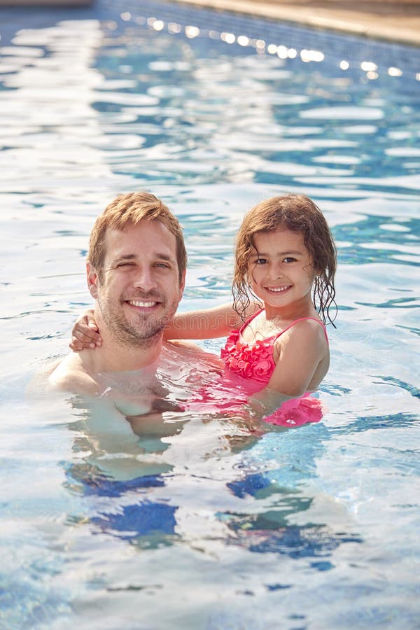 Portrait Of Father And Daughter Having Fun In Swimming Pool On Summer