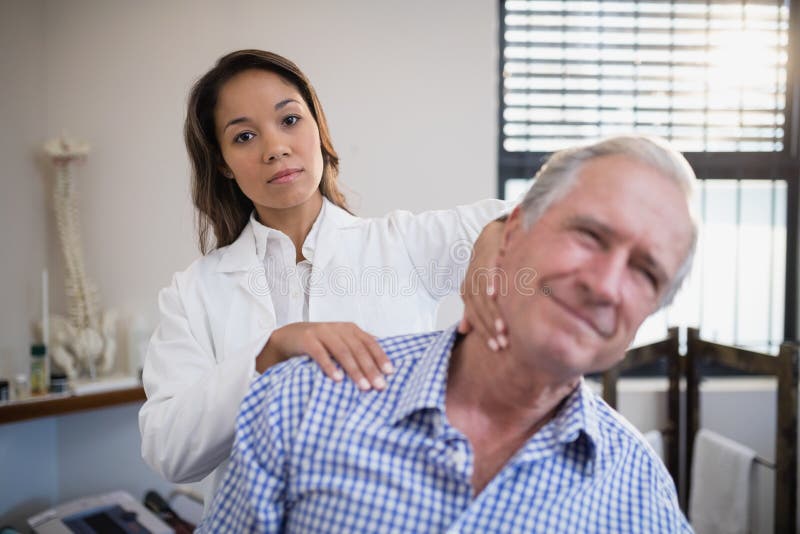 Portrait Of Female Therapist Giving Neck Massage To Senior Male Patient