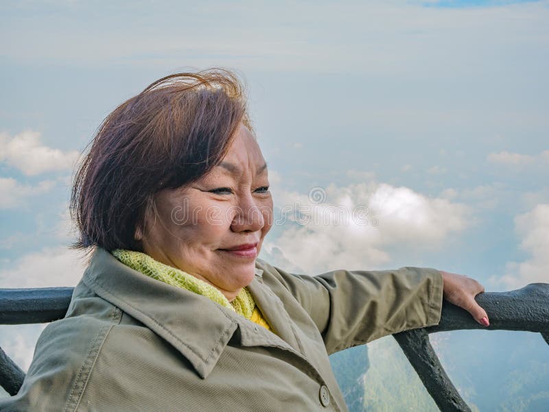 Portrait foto av vackra asiatiska högre kvinnor med vacker syn på Tianmen berget och fritt Sky i staden Zhangjiajie Kina royaltyfri bild Portrait foto av vackra asiatiska högre kvinnor med vacker syn på Tianmen berget och fritt Sky i staden Zhangjiajie Kina royaltyfri bild
