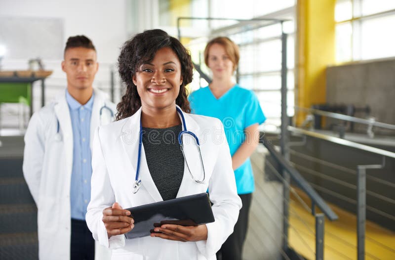 Portrait of a friendly female african american doctor and team in bright modern office royalty free stock image Portrait of a friendly female african american doctor and team in bright modern office royalty free stock image