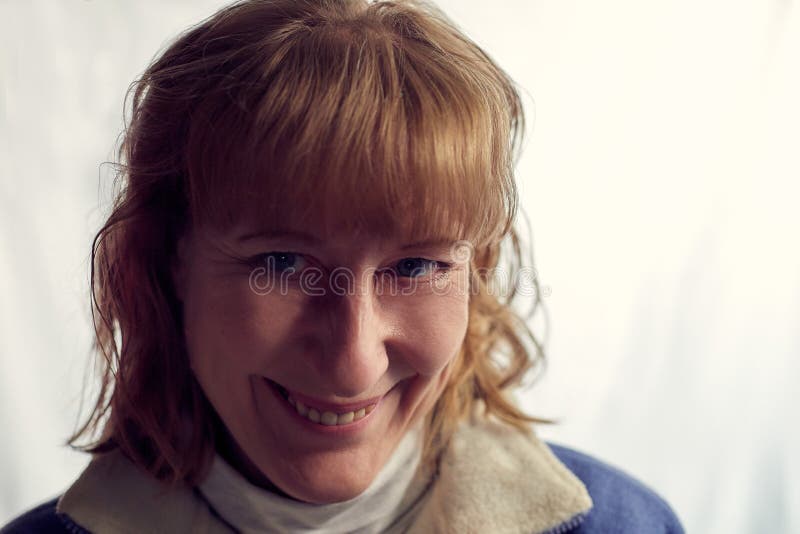 Portrait of fun middle-aged woman on a white background. Unprofessional female model with shy smile awkwardly posing in the Studio.