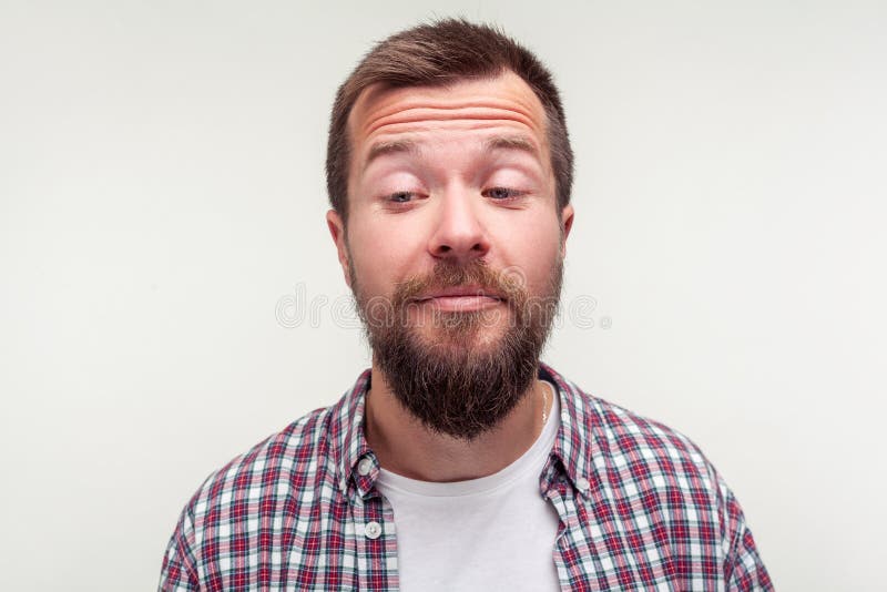 Portrait of funny awkward bearded man standing with crossed eyes, comic silly expression. isolated on white background