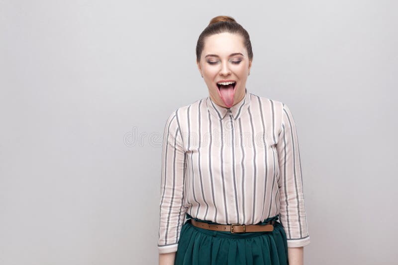 Portrait of funny crazy beautiful young woman in striped shirt with makeup and collected ban hairstyle, standing with closed eyes royalty free stock image