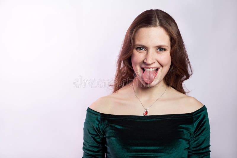 Portrait of funny crazy woman with freckles and classic green dress with tongue. royalty free stock photo