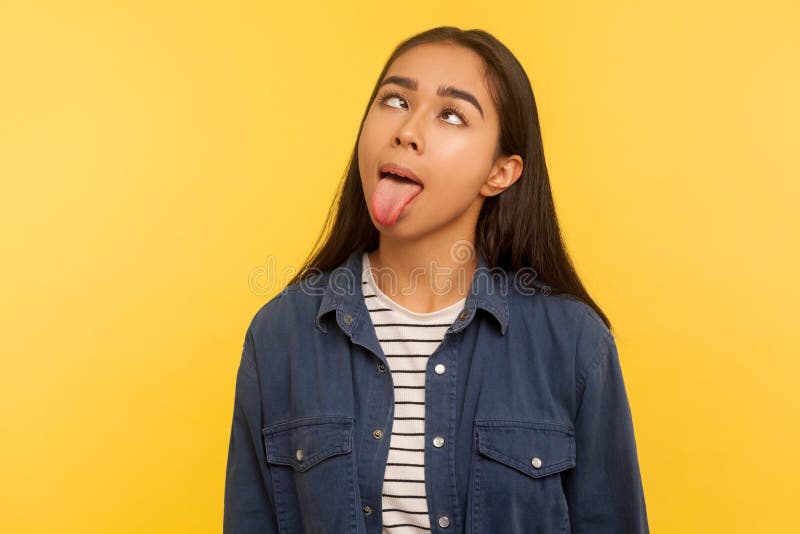 Portrait of funny dumb crazy girl in denim shirt showing tongue out and loo...