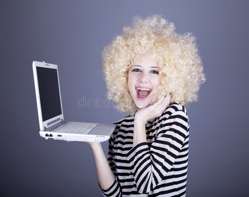 Portrait of funny girl in blonde wig with laptop.