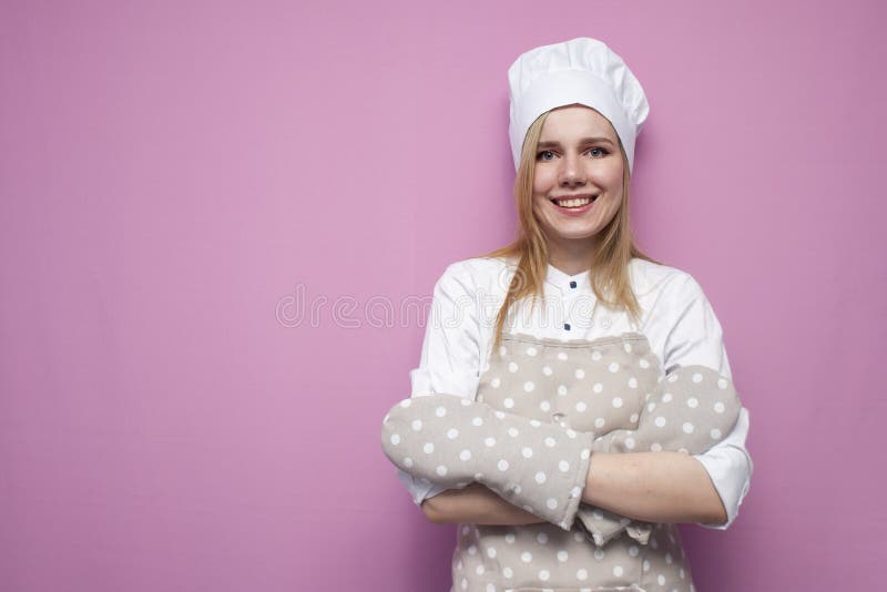 Portrait of a funny girl cook in uniform, apron and gloves for baking on a colored background, a beautiful woman is a housewife in stock image Portrait of a funny girl cook in uniform, apron and gloves for baking on a colored background, a beautiful woman is a housewife in stock image