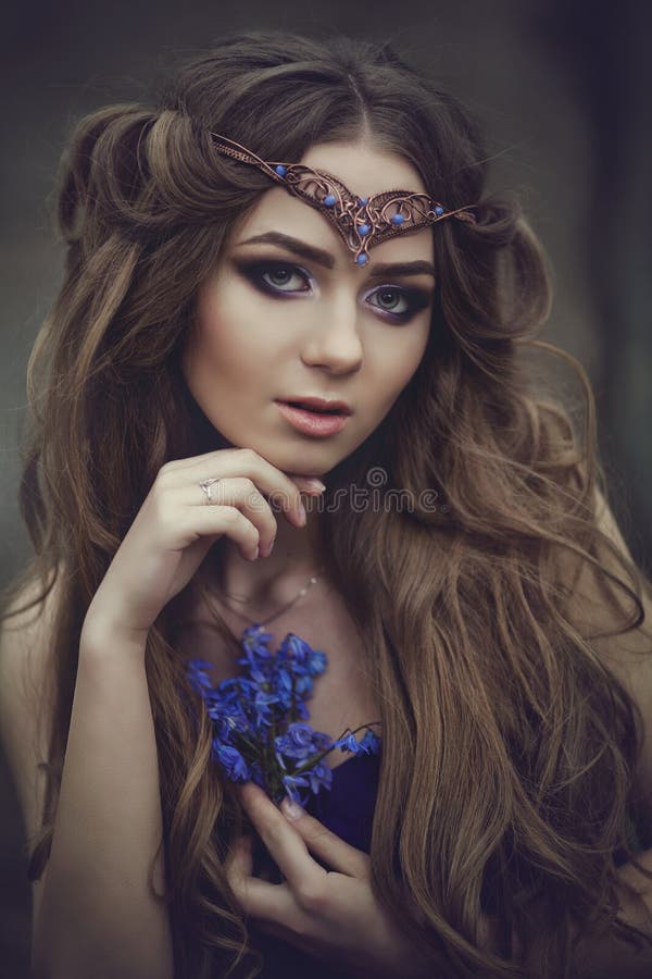Portrait of a girl elf with long hair and blue eyes, wears a tiara with a bouquet of spring flowers in the forest. Girl