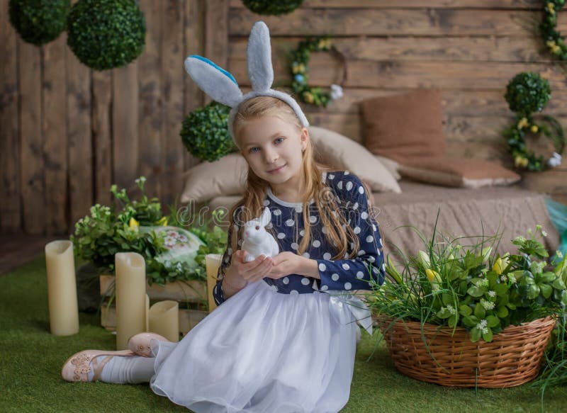 Portrait of girl having fun on Easter wearing bunny ears and holding eggs on eyes during spring season