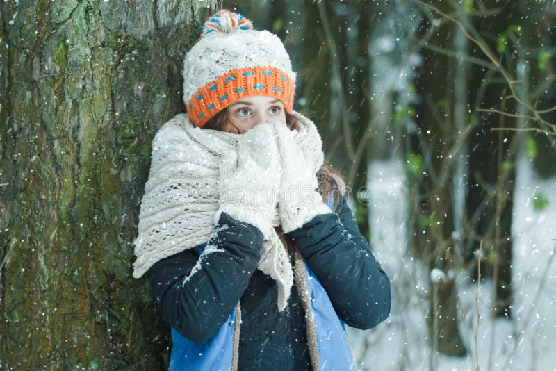 Portrait of girl hiding her face with wooly knitted bulky scarf during winter frost snowfall outdoors