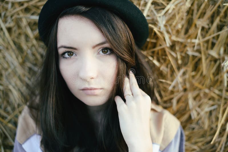 Portrait of girl hipster against hay bale in fall