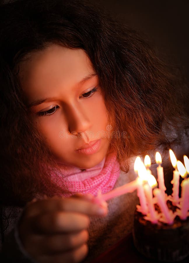 De 10 anos, morena, las luces rosa velas sobre el festivo pastel.