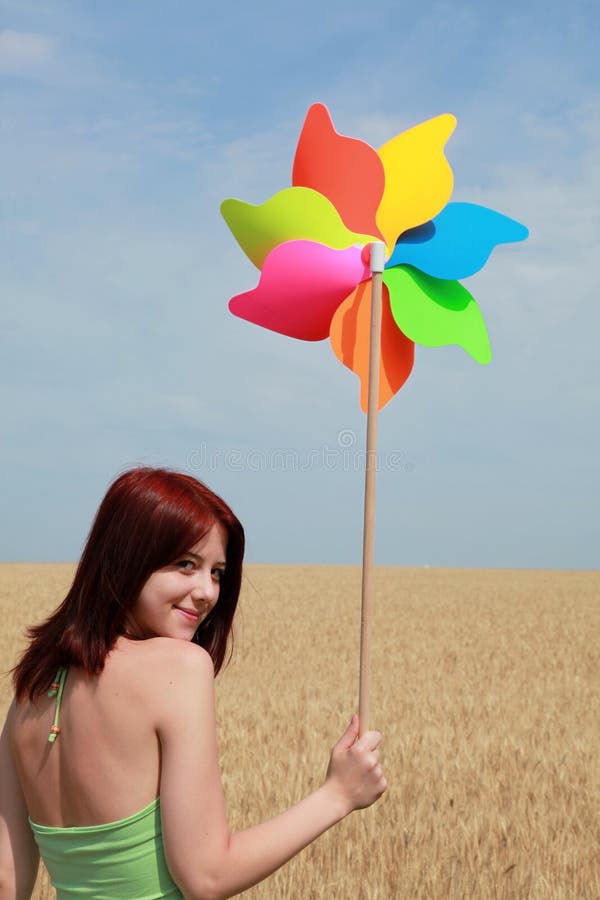 Portrait of girl with wind turbine at wheat field