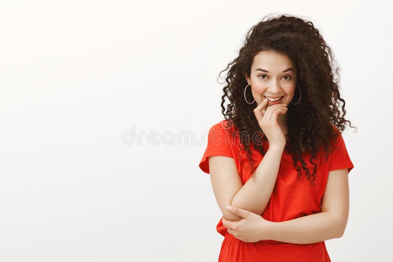 Portrait of good-looking flirty femenine girl with curly hair, smiling intriguingly and holding hand on ching, crossing royalty free stock images Portrait of good-looking flirty femenine girl with curly hair, smiling intriguingly and holding hand on ching, crossing royalty free stock images