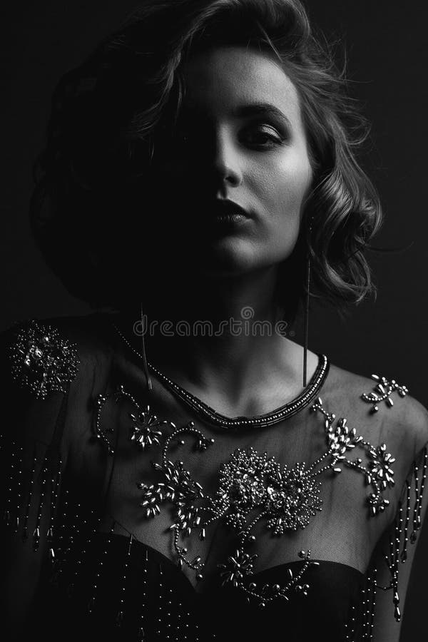 Portrait of gorgeous brunette model with curly hair and beautiful makeup posing with contrast light. Black and white toning