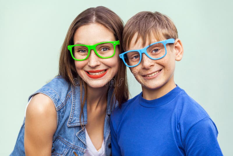 Portrait of gorgeous freckled brother and sister in casual t shirts wearing trendy glasses and posing over light blue background