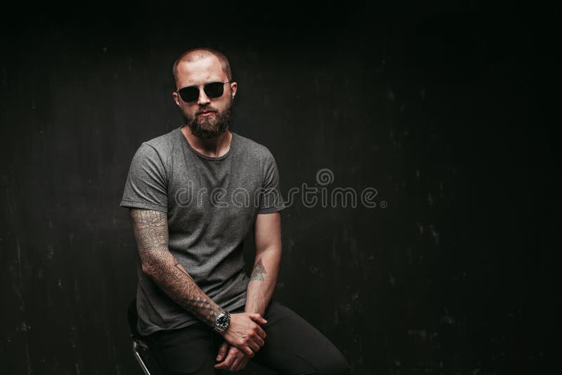 Portrait of a handsome balded man with long well trimmed beard wearing sunglasses and grey shirt looking at camera stock photography Portrait of a handsome balded man with long well trimmed beard wearing sunglasses and grey shirt looking at camera stock photography
