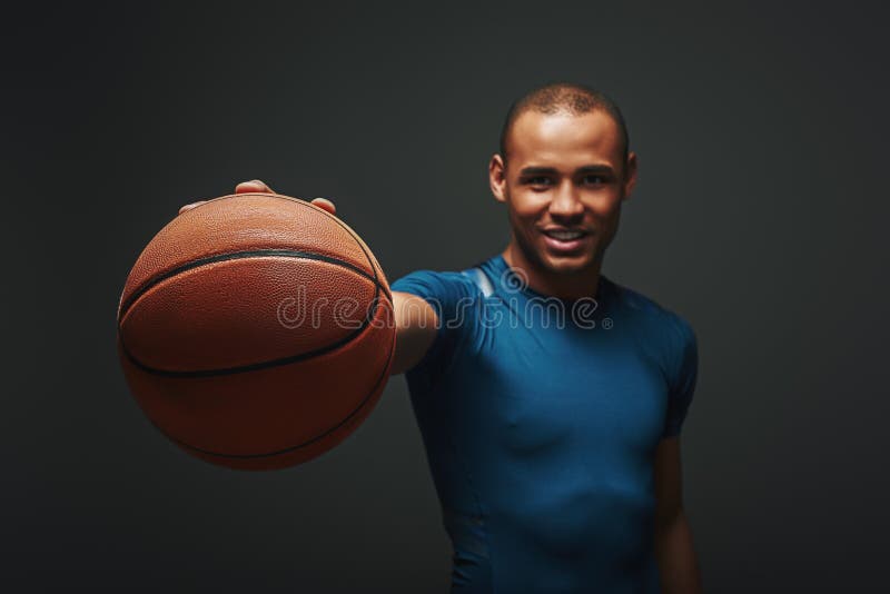 Dont give up! Smiling athlete stretches out his hand with the ball standing over dark background royalty free stock images Dont give up! Smiling athlete stretches out his hand with the ball standing over dark background royalty free stock images