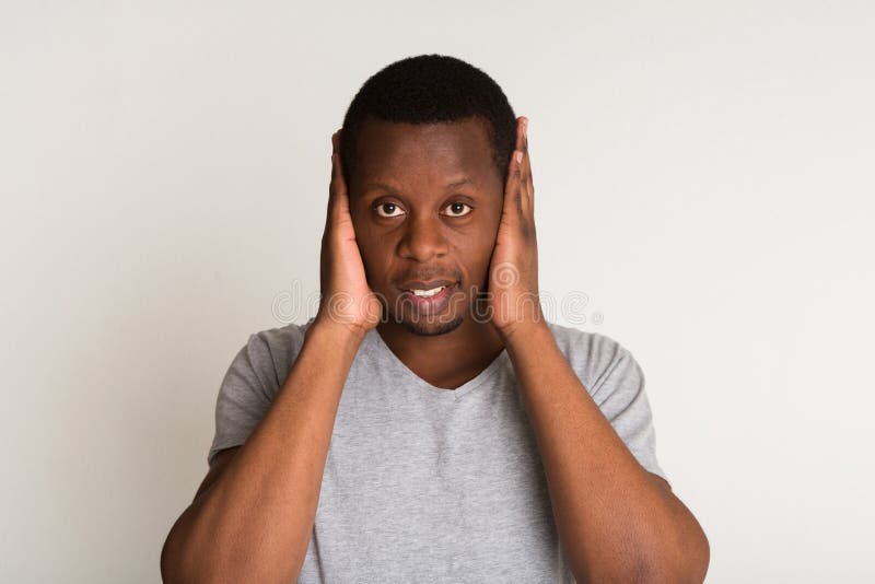 Portrait of handsome black man covering ears isolated on white background