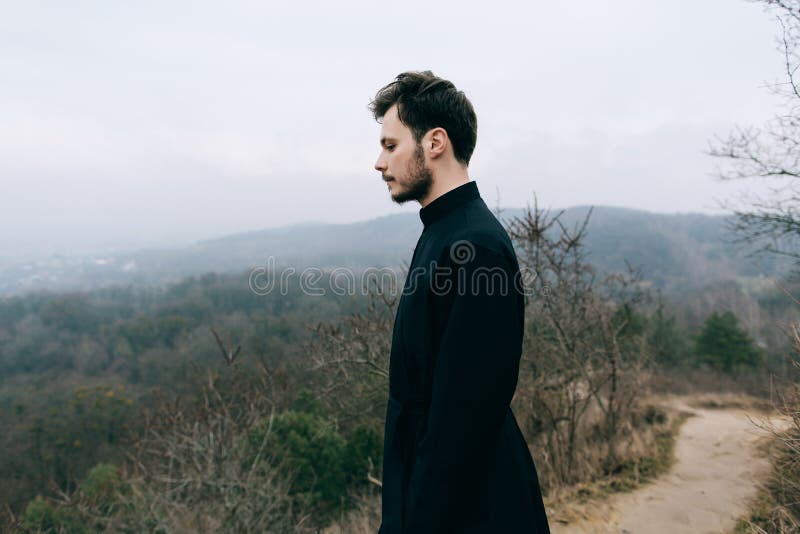 Portrait of handsome catholic bearded man priest or pastor posing outdoors in mountains stock image