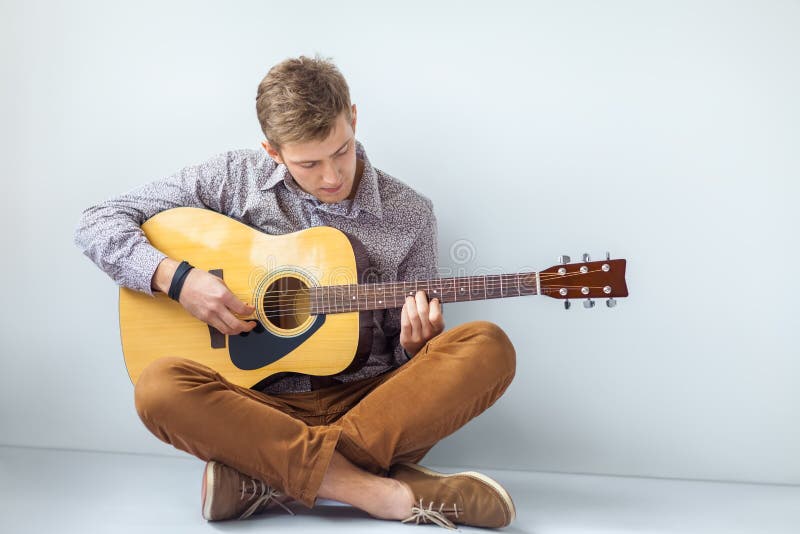 Portrait of handsome man playing guitar siting on floor royalty free stock photo Portrait of handsome man playing guitar siting on floor royalty free stock photo