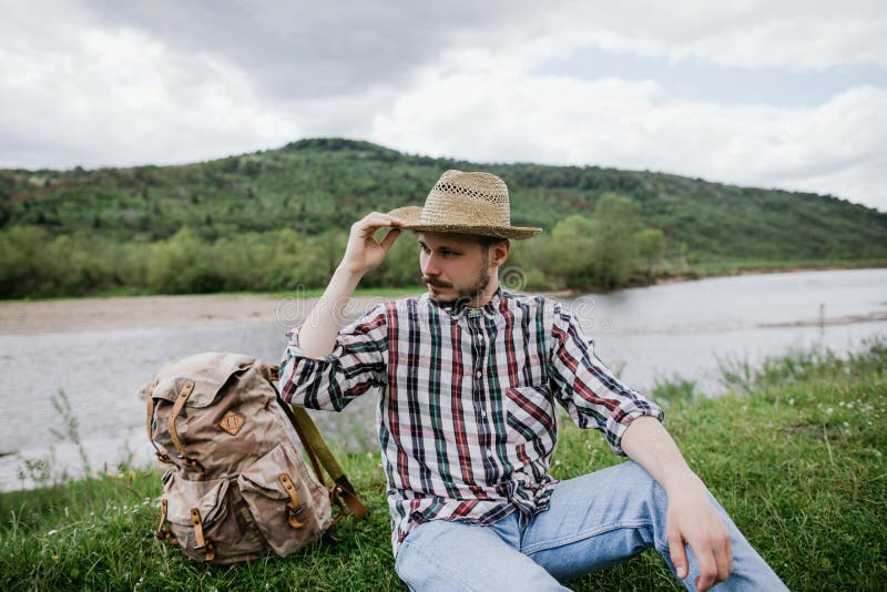 Portrait of a handsome young bearded hipster man in a straw hat outdoors stock photo