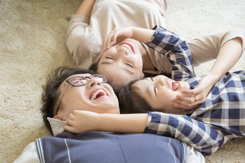 Portrait Happy Asian Family laying down and playing in living room.