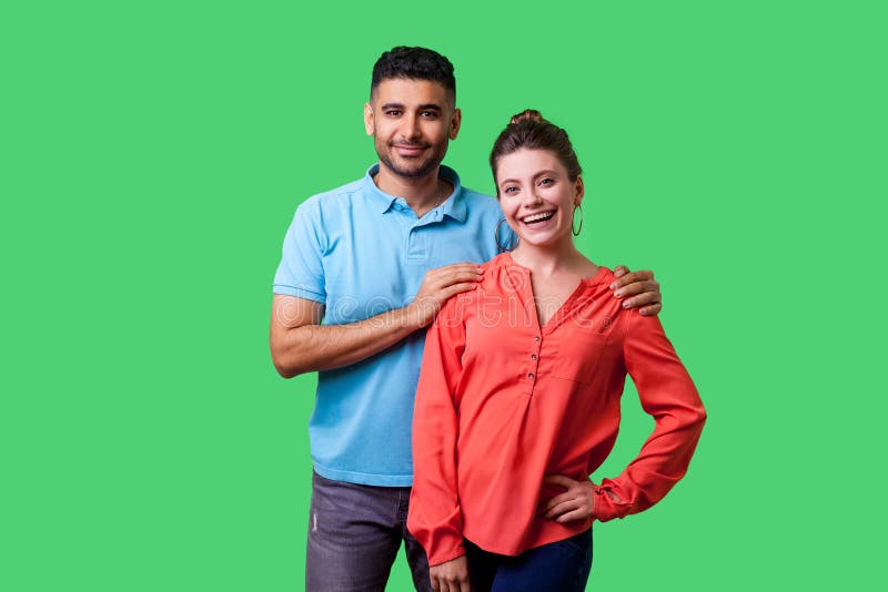 Portrait of happy attractive young couple in casual wear standing together. isolated on green background