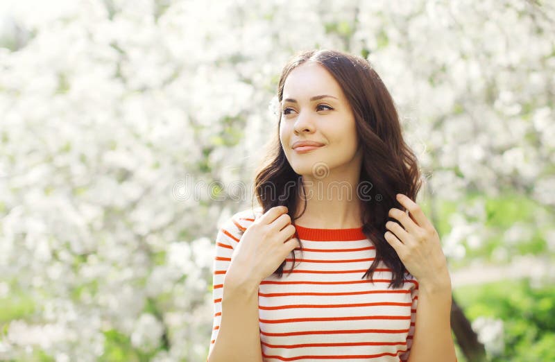 Portrait of happy beautiful young woman in flowering garden