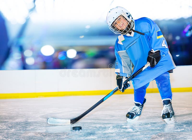 Happy little hockey player passing the puck.