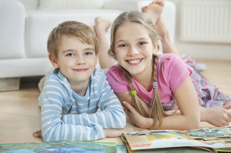 Portrait of happy brother and sister with story books while lying on floor