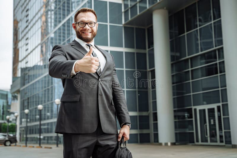 Portrait of a happy business man showing his thumb up on the background of the business center royalty free stock photography Portrait of a happy business man showing his thumb up on the background of the business center royalty free stock photography
