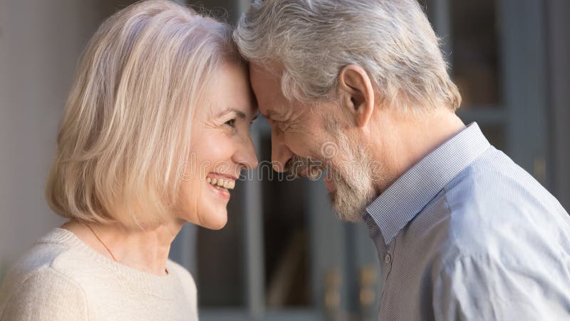 Happy mature couple touch foreheads enjoying romantic moment