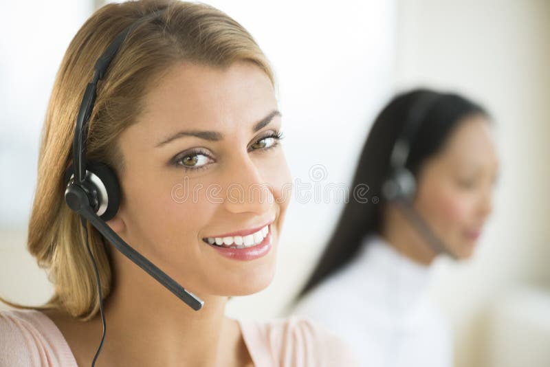 Close-up portrait of happy female customer service representative with colleague in background