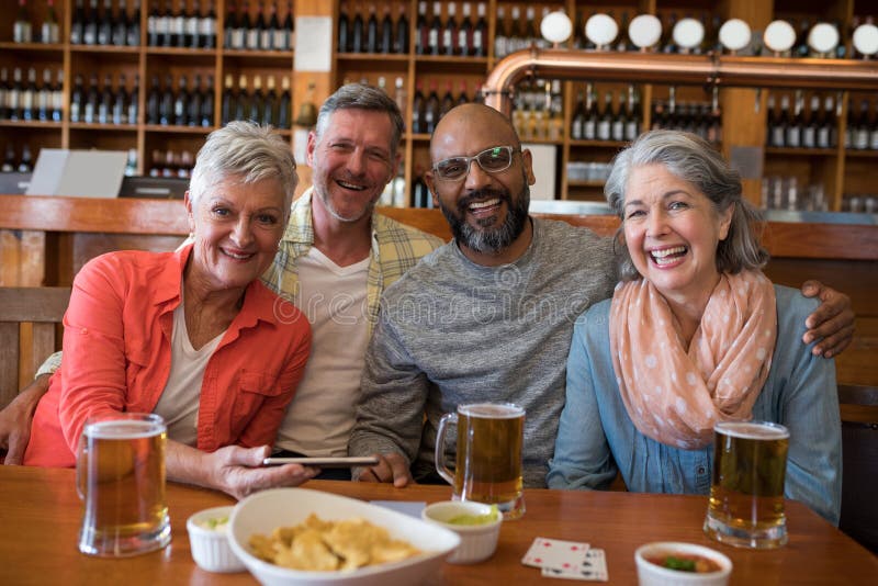 Happy friends sitting together at bar stock photography