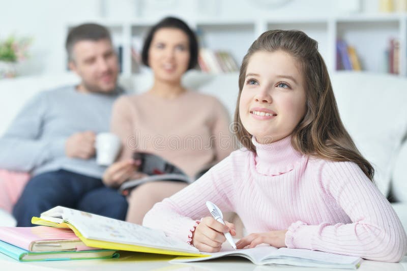 Portrait of Happy girl with book at home, parents on background