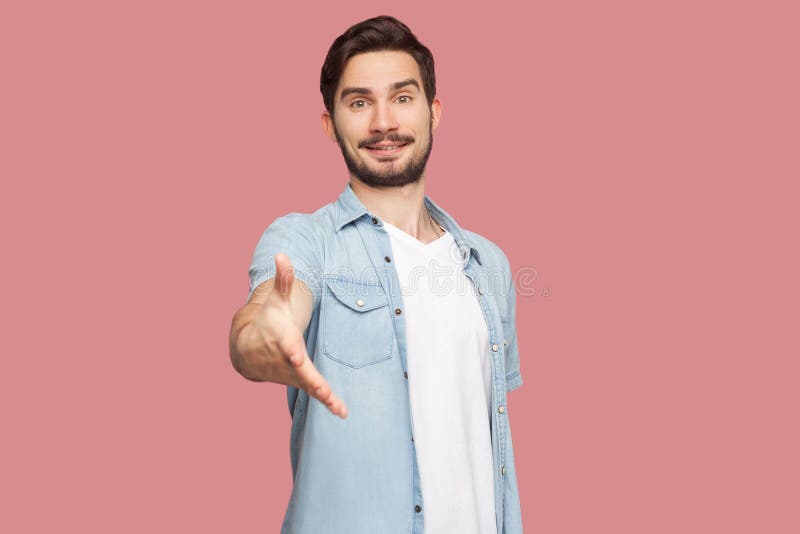 Portrait of happy handsome bearded young man in blue casual style shirt standing, looking at camera with toothy smile and giving royalty free stock images Portrait of happy handsome bearded young man in blue casual style shirt standing, looking at camera with toothy smile and giving royalty free stock images